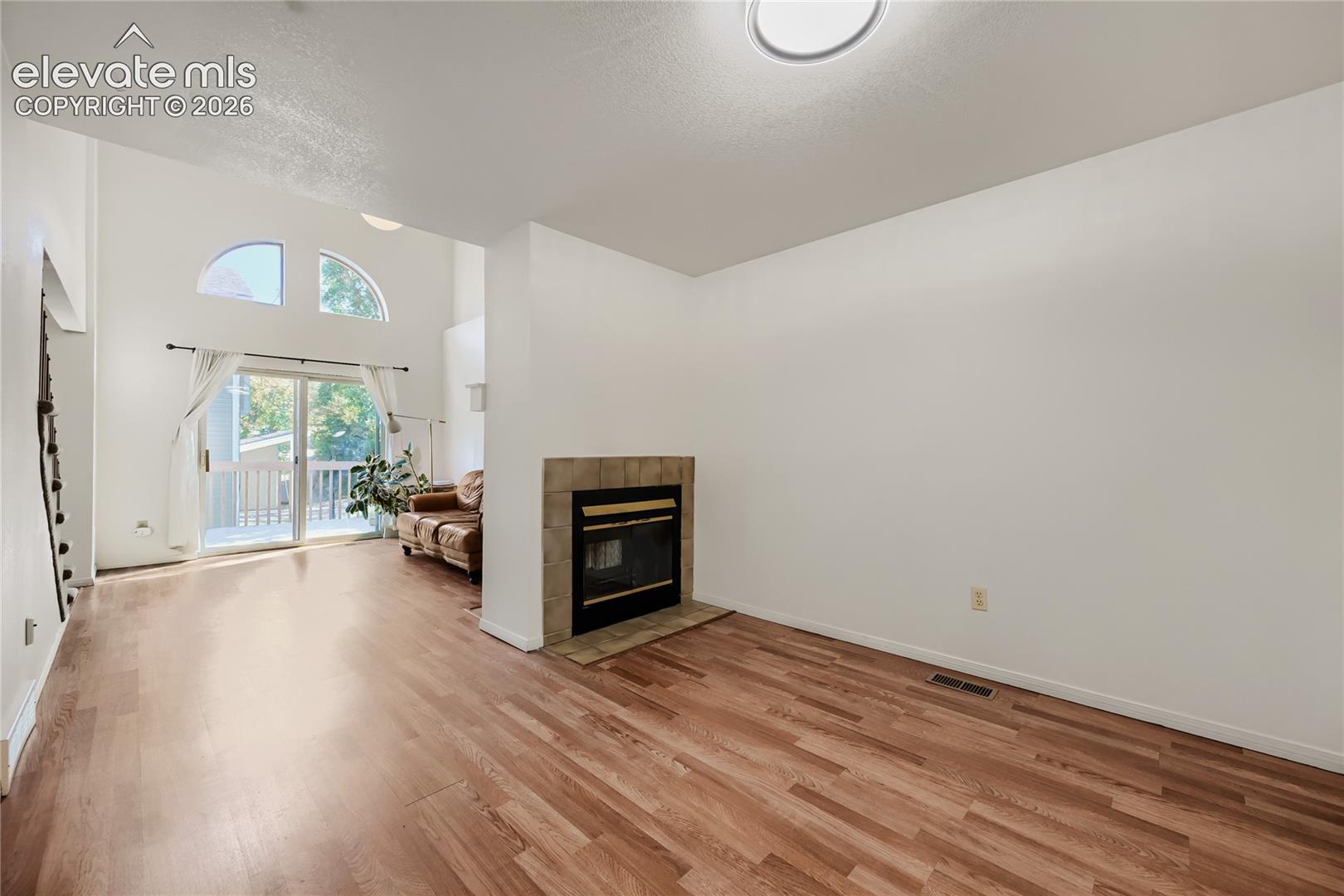 Wood-finish flooring, high ceilings, arched transom windows, and a tiled fireplace surround