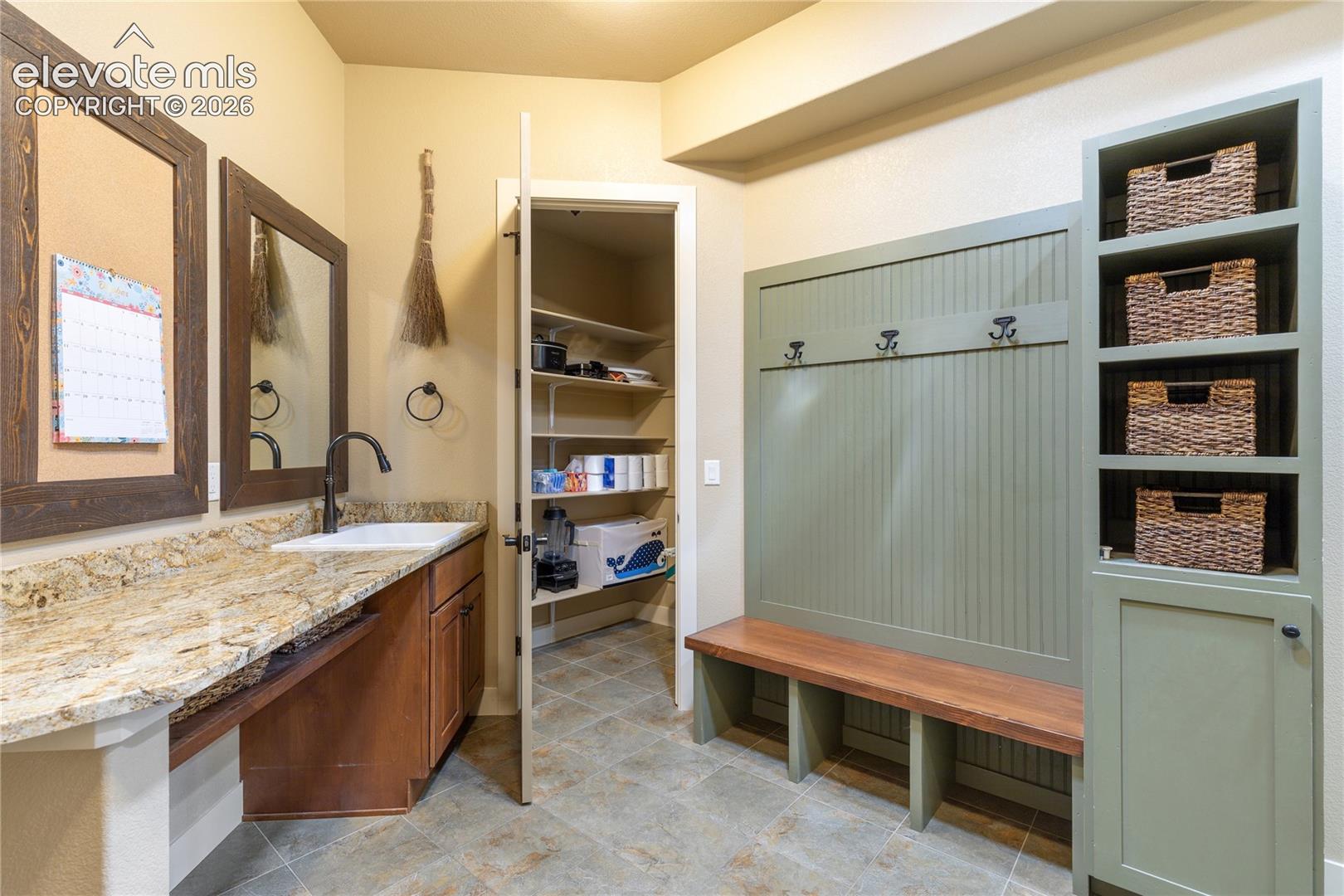 The thoughtfully designed mudroom features custom cabinetry, a granite-topped utility sink + dedicated storage for everyday organization.