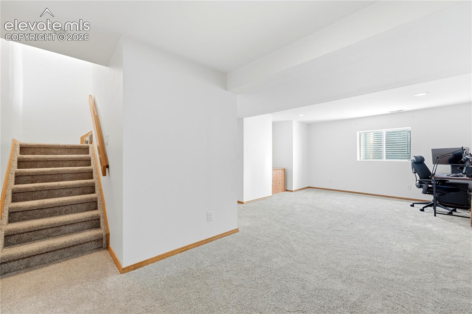 Spacious room featuring light-colored carpeting, white walls, and a window well