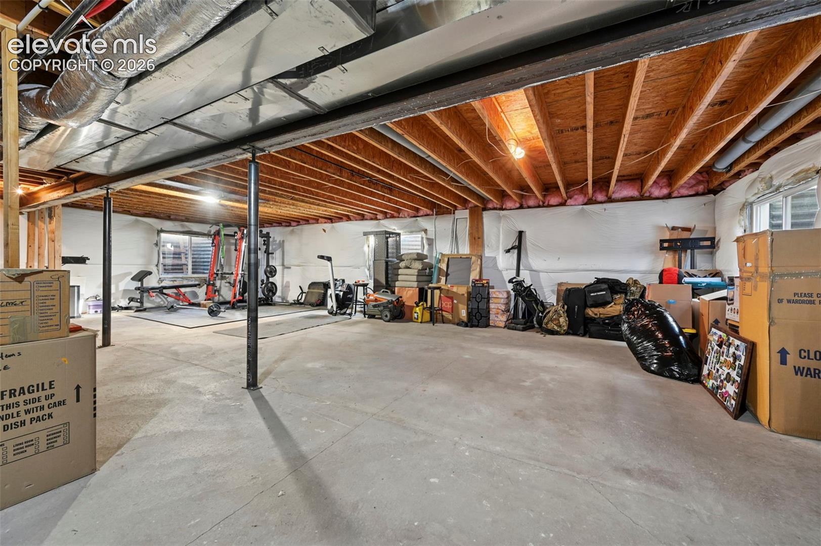 Expansive unfinished lower level featuring exposed joists, concrete flooring, and multiple support columns