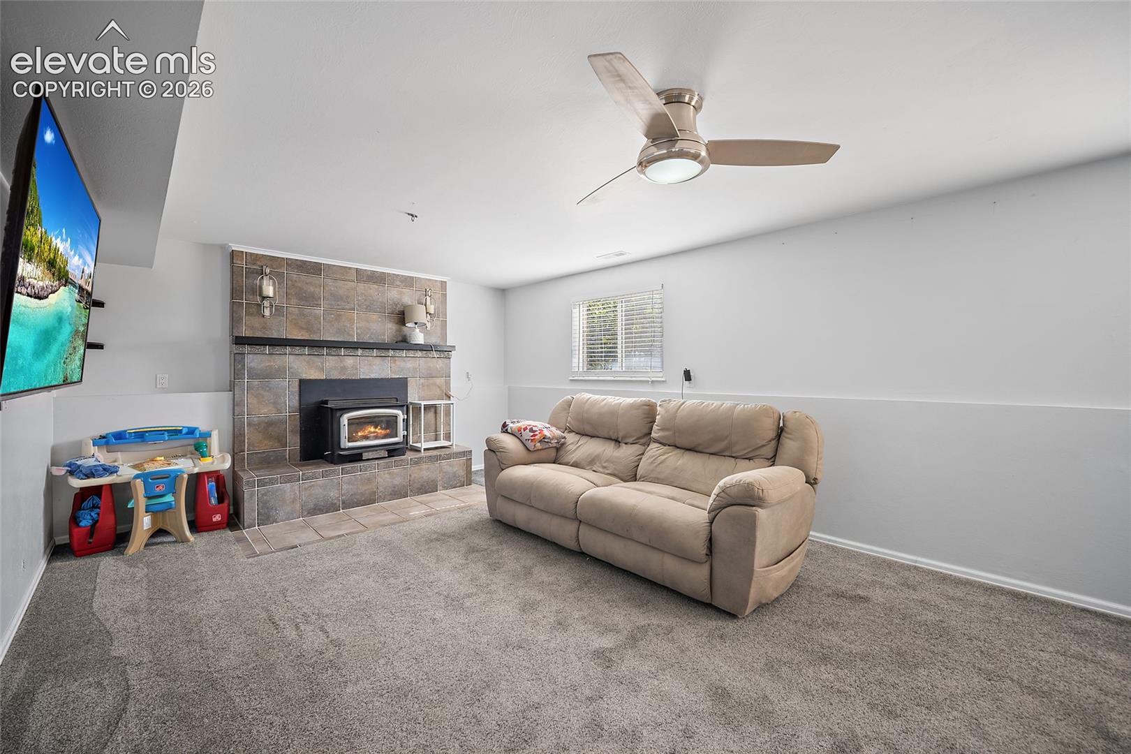 Family room with fireplace and ceiling fan.