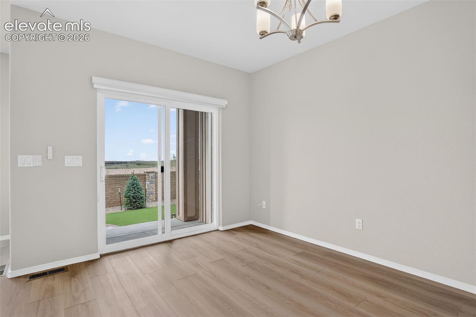 Spacious room featuring wood-finish flooring and a sliding glass door