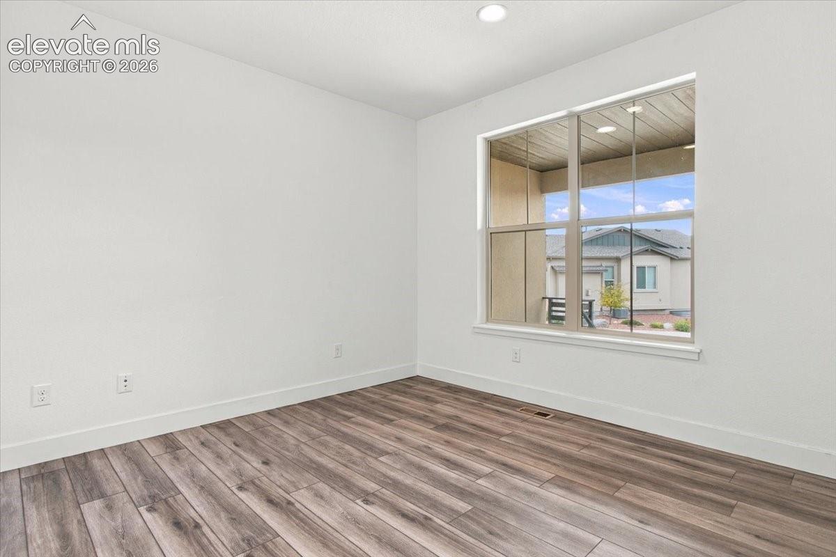 Wood-finish flooring, neutral walls, recessed ceiling lighting, and a large multi-pane window