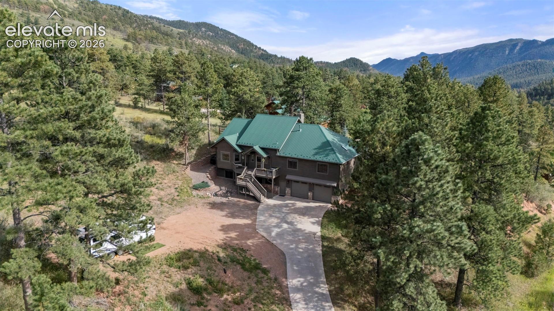 Aerial view of property and surrounding area featuring a heavily wooded area and a mountain backdrop