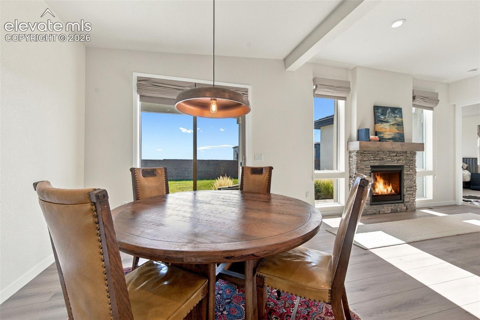 Floor-to-ceiling windows, stone-surround fireplace with a wooden mantel, recessed lighting, and wood-finish flooring