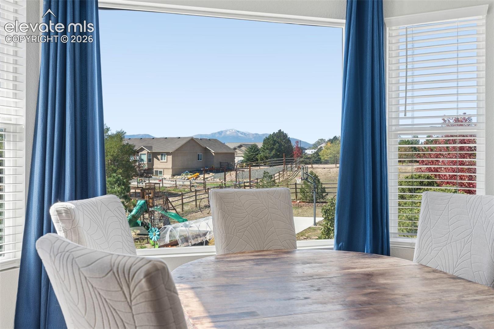 Expansive picture window offering a mountain backdrop and Pikes Peak, complemented by white window blinds and blue drapery