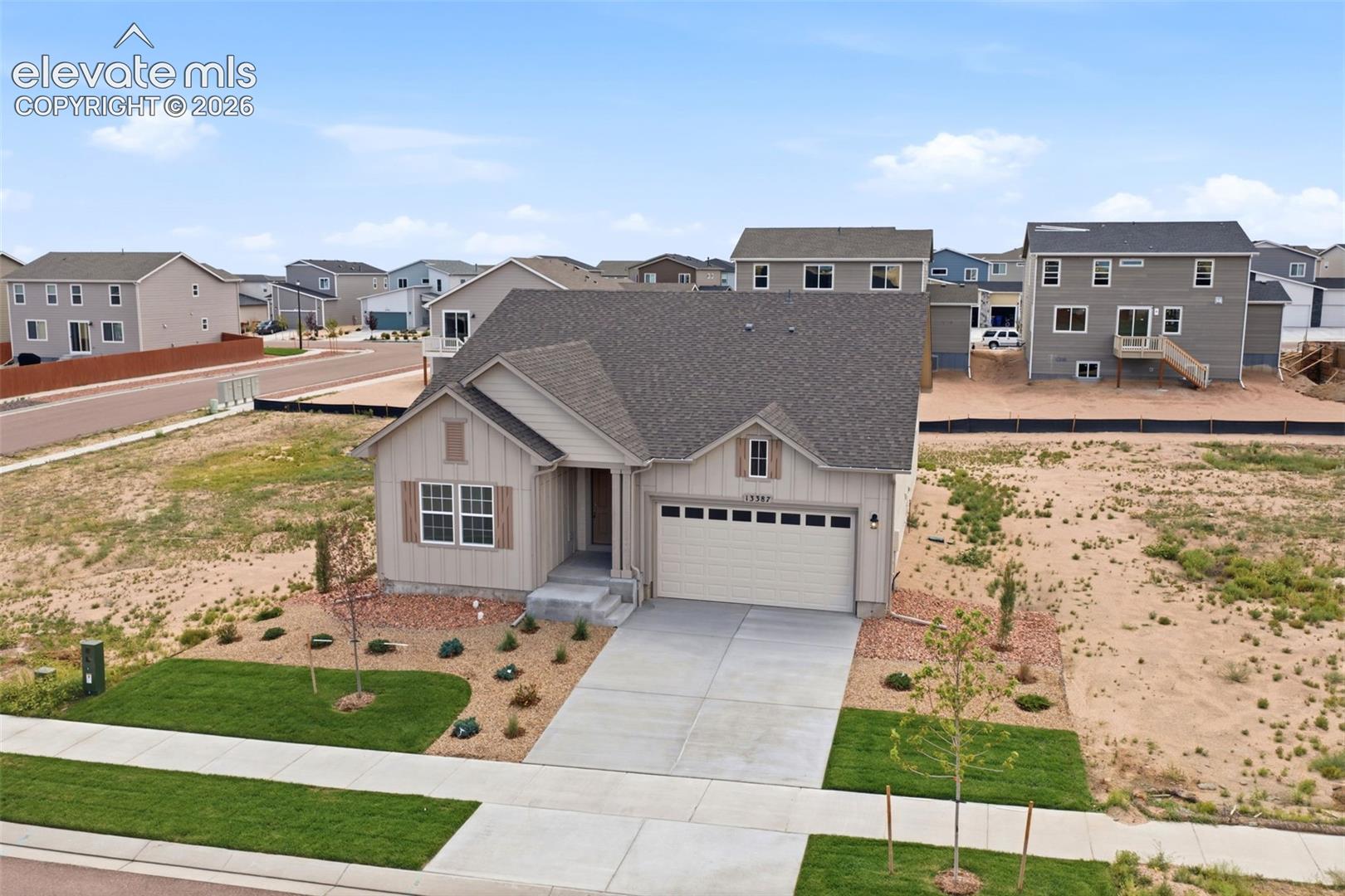Single-story residence featuring a multi-gabled roofline, vertical panel siding, attached two-car garage, and concrete driveway