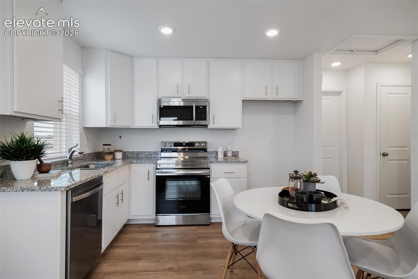 White cabinetry, stainless steel appliances, granite countertops, wood-finish flooring, and recessed lighting
*photos of a model home*