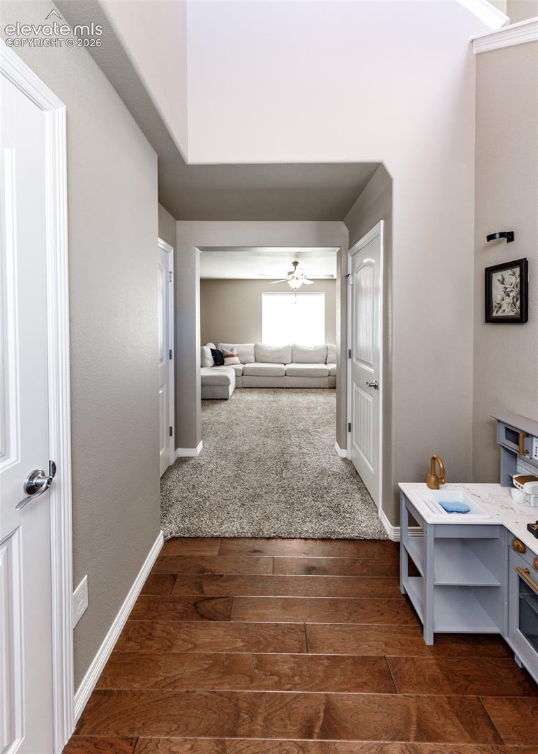 Interior hallway featuring wood-finish flooring, vaulted ceilings, and multi-panel interior doors with brushed nickel hardware