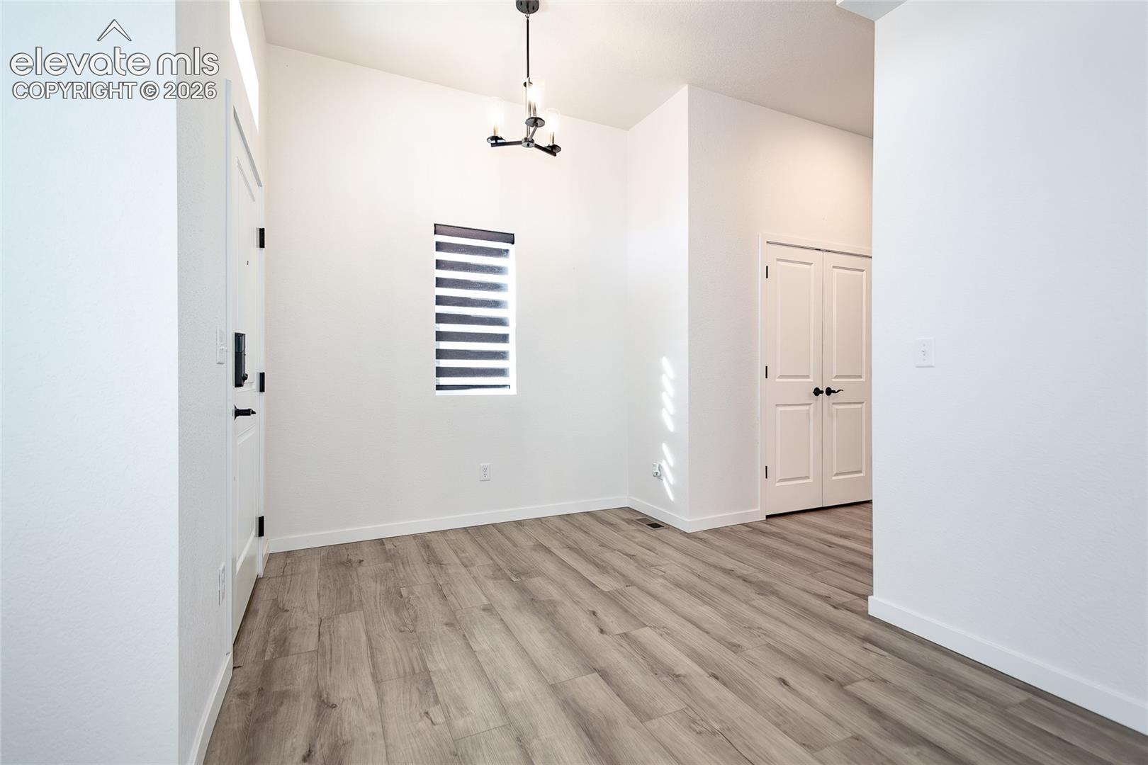 Entryway featuring wood-finish flooring, vaulted ceilings, a geometric chandelier, and double-panel doors