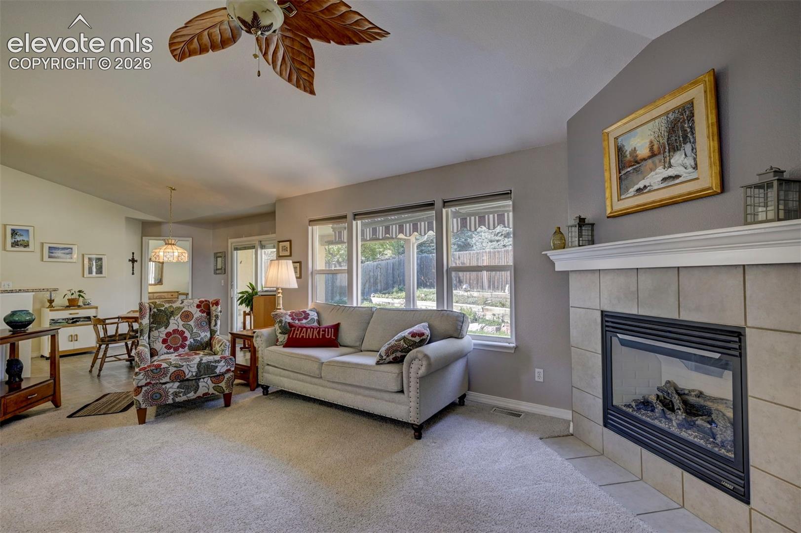 Living room featuring large windows for natural light, a fireplace and lofted ceiling.
