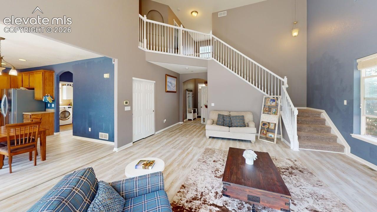 Two-story great room with a staircase featuring white railings and carpeted treads