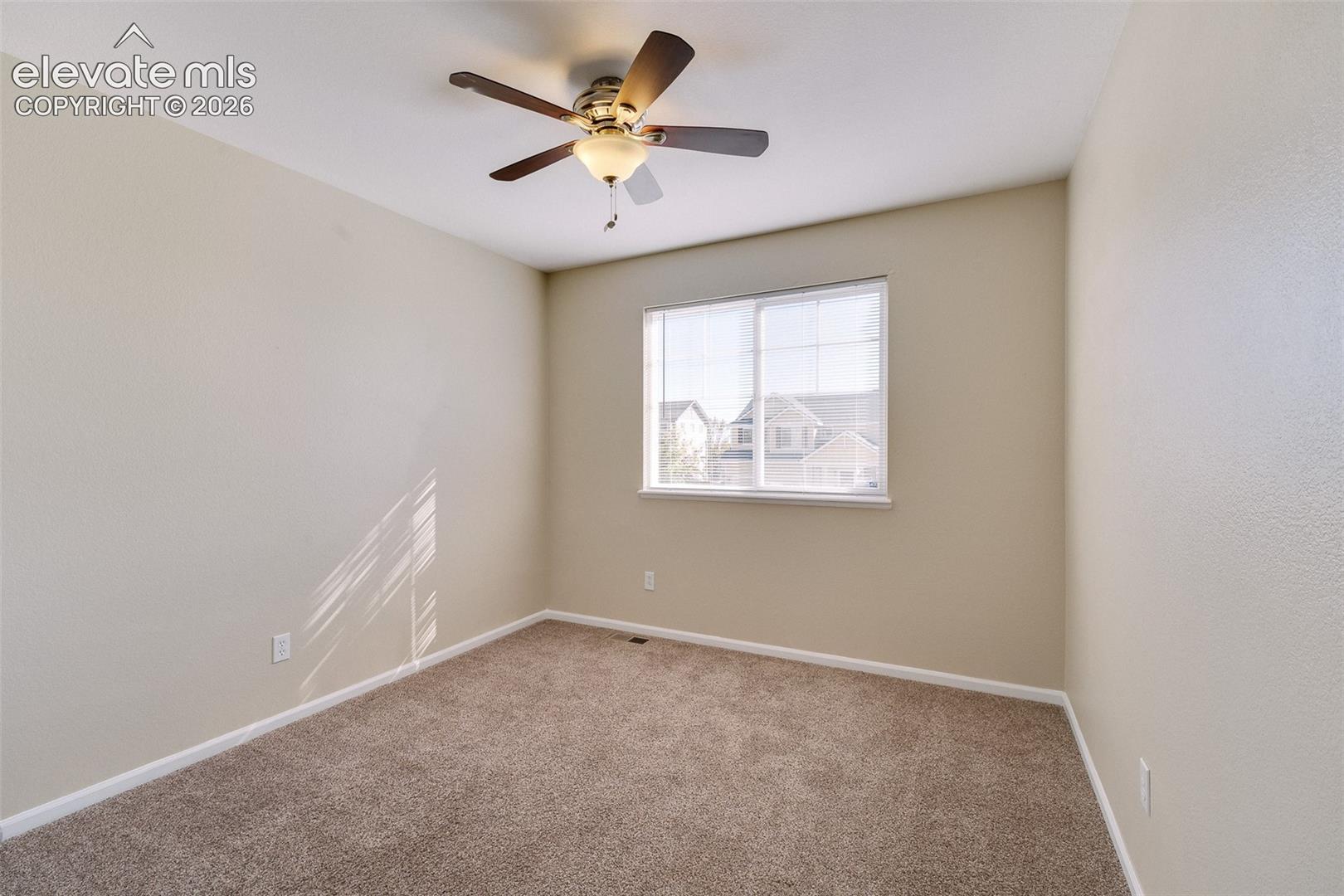 Neutral-toned room featuring carpeting, a multi-blade ceiling fan with an integrated light fixture, and a single-pane sliding window