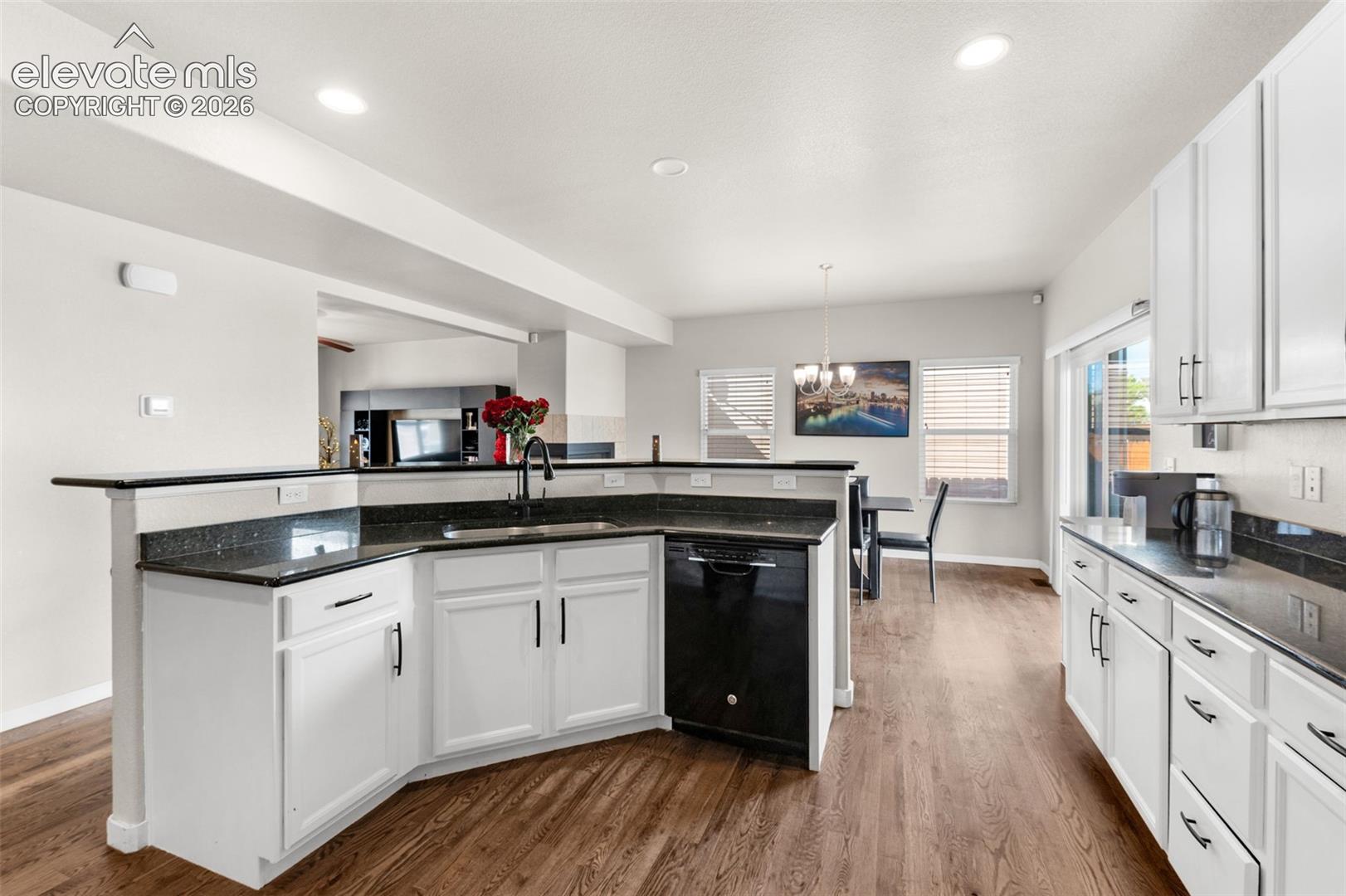 Kitchen featuring white cabinetry, dark stone countertops, recessed lighting, wood-finish flooring, and a black dishwasher