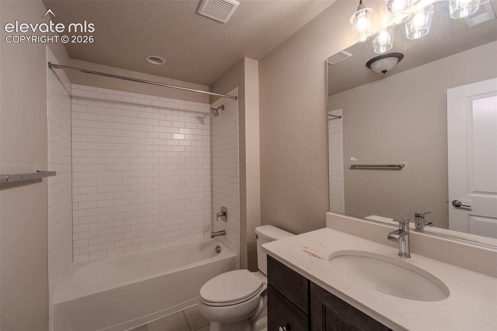 Lower Level Full Bathroom with vanity, mirror, and tiled tub/shower.