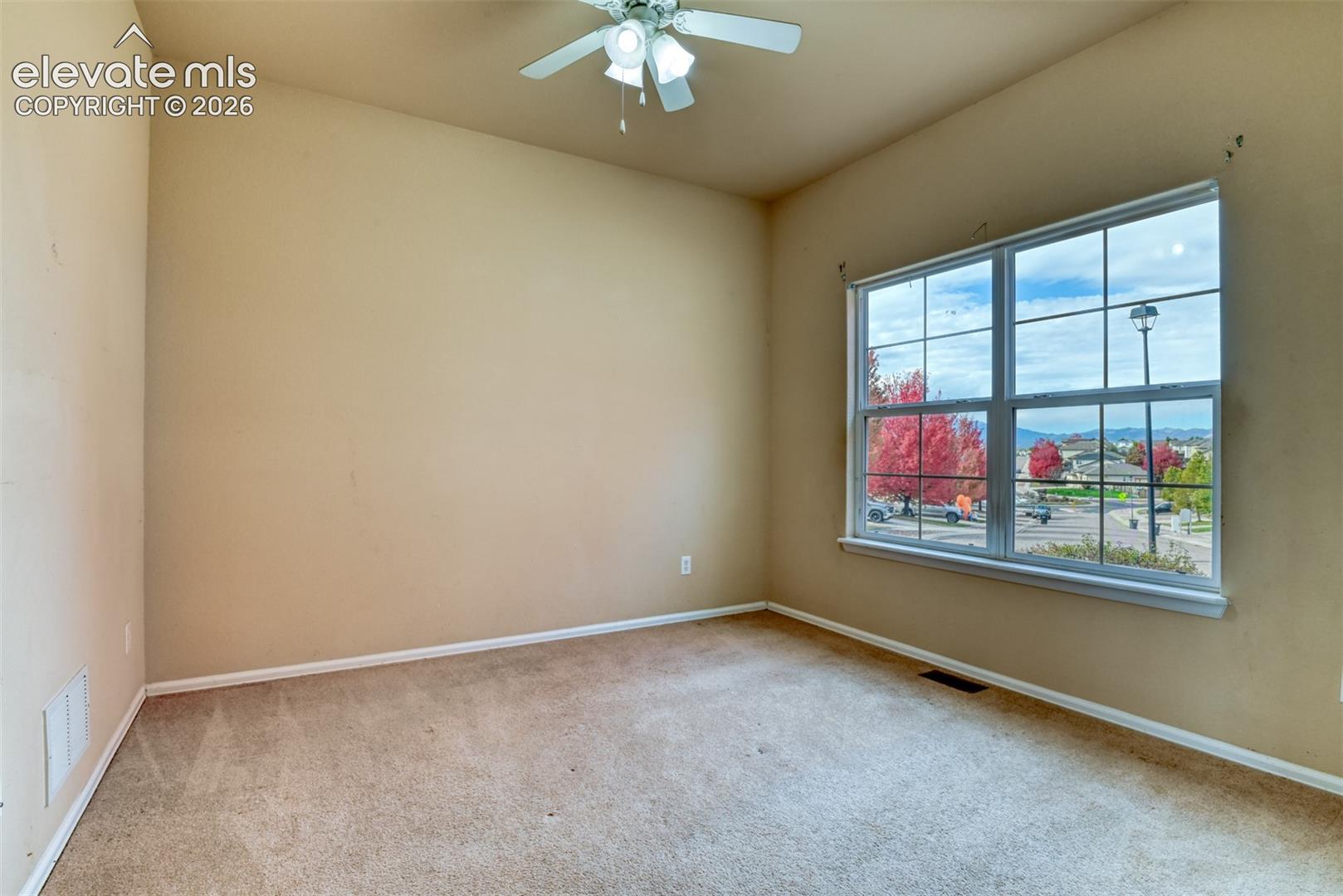 Neutral-toned room featuring plush wall-to-wall carpeting, high ceilings, a multi-light ceiling fan, and a large multi-pane window with mountain and landscape scenery