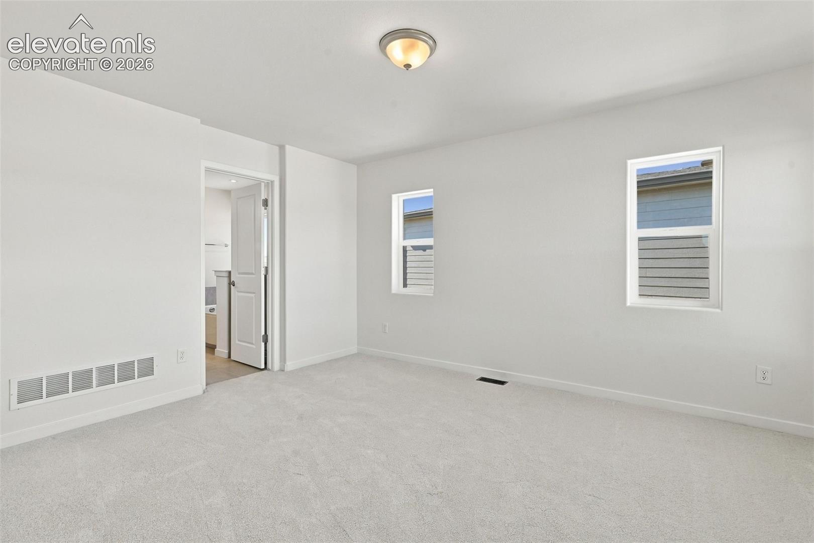 Spacious room with light-toned carpeting and multiple windows