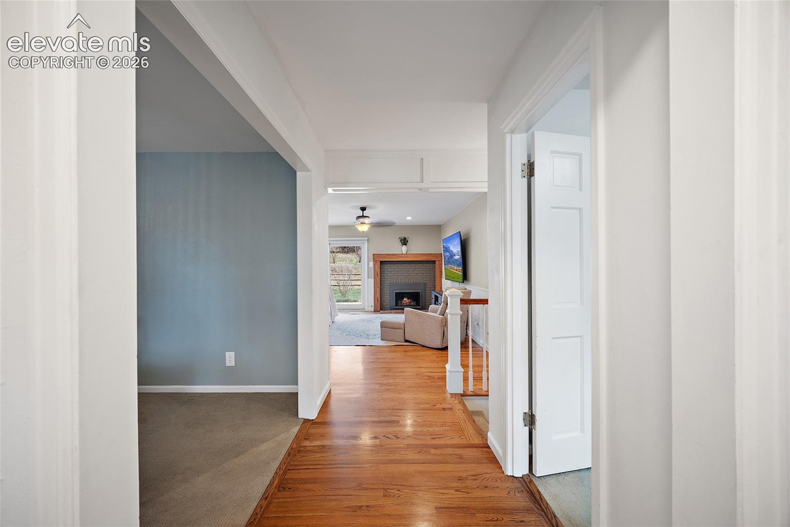 Wood-finish flooring, fireplace with a tiled surround and wood mantel, and white interior doors