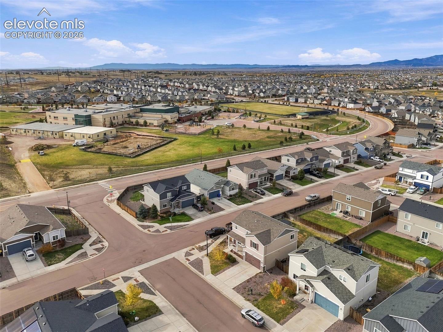 Aerial perspective showcasing a planned suburban residential development featuring multi-level dwellings, paved street infrastructure, and mountain topography in the distance