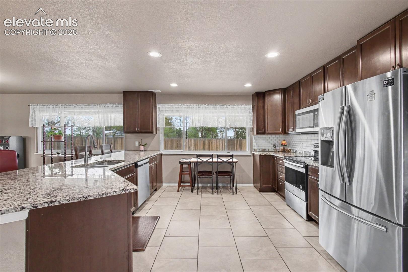 Granite countertops, stylish backsplash, stainless steel appliances, and ample cabinetry, offering a functional and inviting space for cooking and gathering.