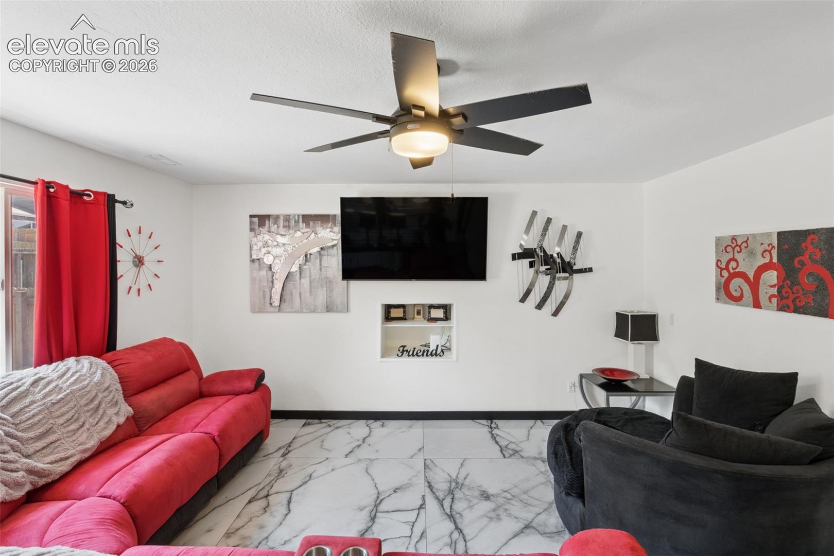 White walls with dark trim, marbling tile flooring, built-in shelving, black ceiling fan with integrated lighting, and a sliding glass door