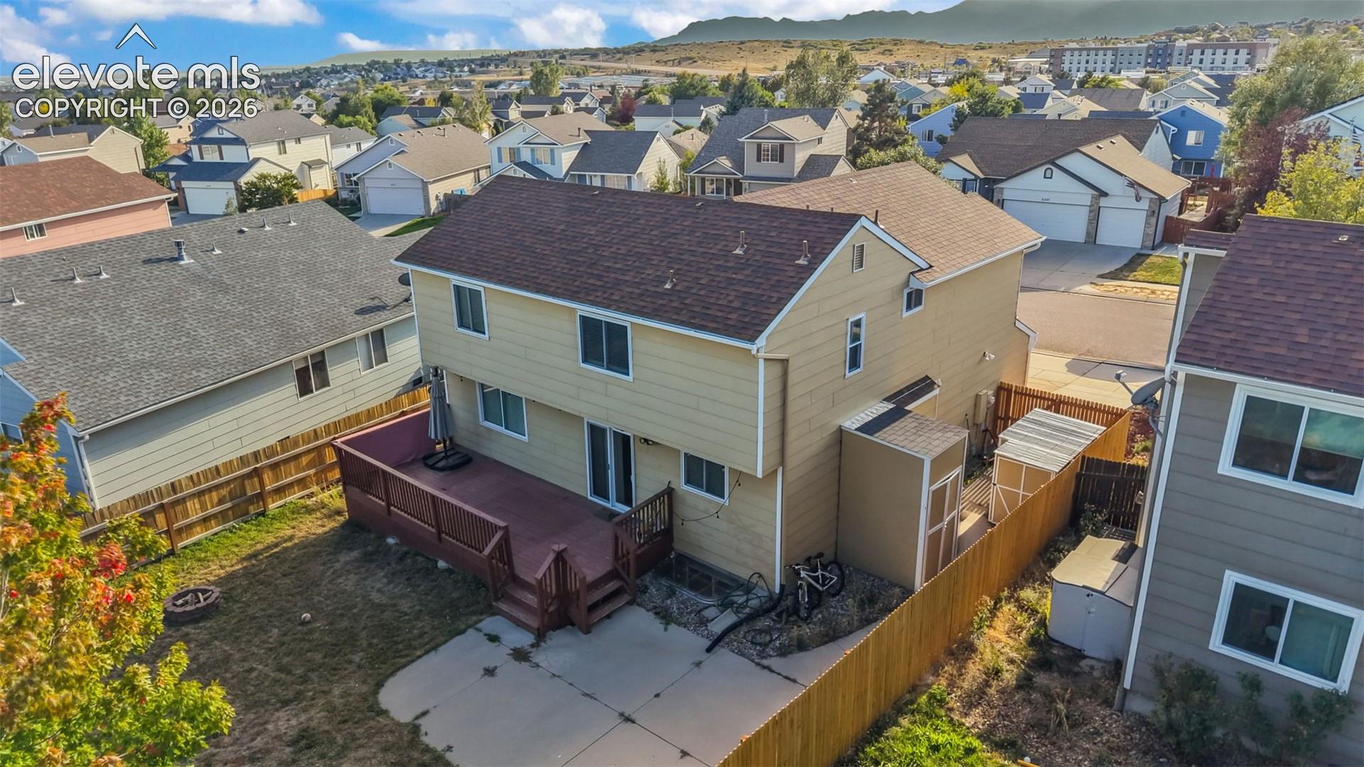 Two-story residential property with a rear deck, concrete patio, and fenced perimeter