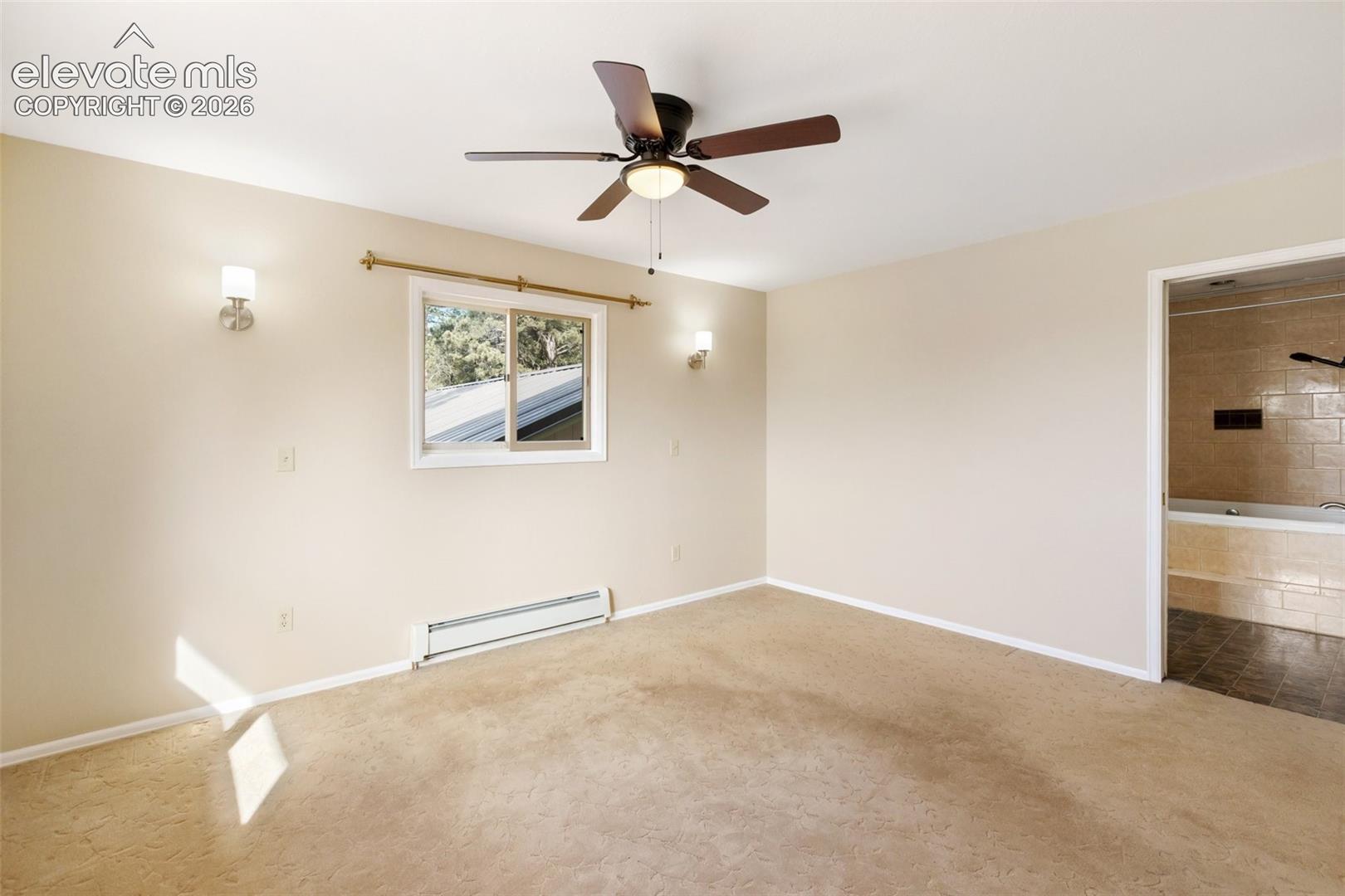 Spacious room featuring a ceiling fan, wall sconces, window, and neutral carpeting