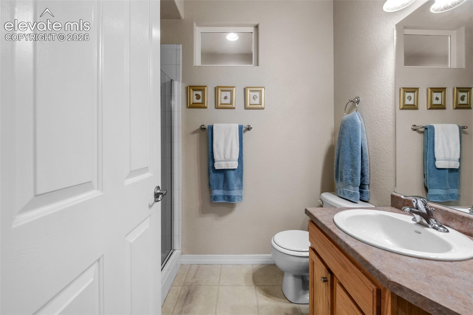 Bathroom with a wood-finish vanity, integrated sink, and an enclosed shower