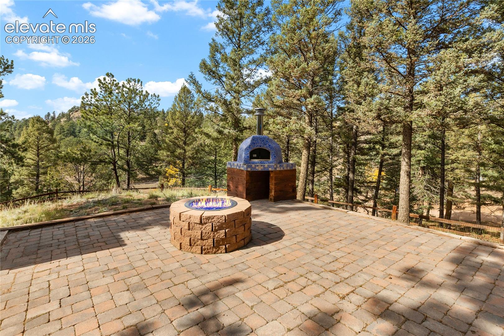 Outdoor patio featuring paver stones, a circular stone fire pit, and a tiled masonry oven
