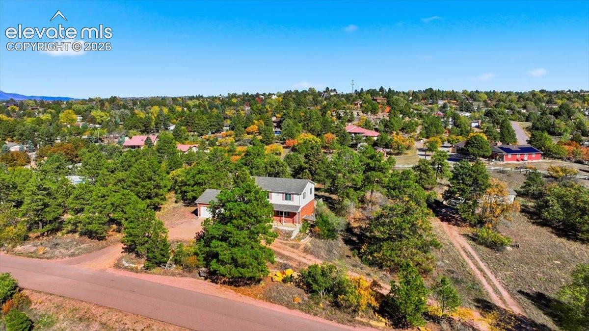 Two-story residence situated on a multi-level lot featuring mature evergreen trees and native vegetation