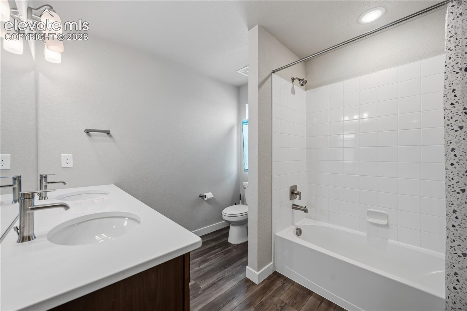 Upper Level Full Bathroom with LVP flooring, dual sink vanity, mirror, and tiled tub/shower.
