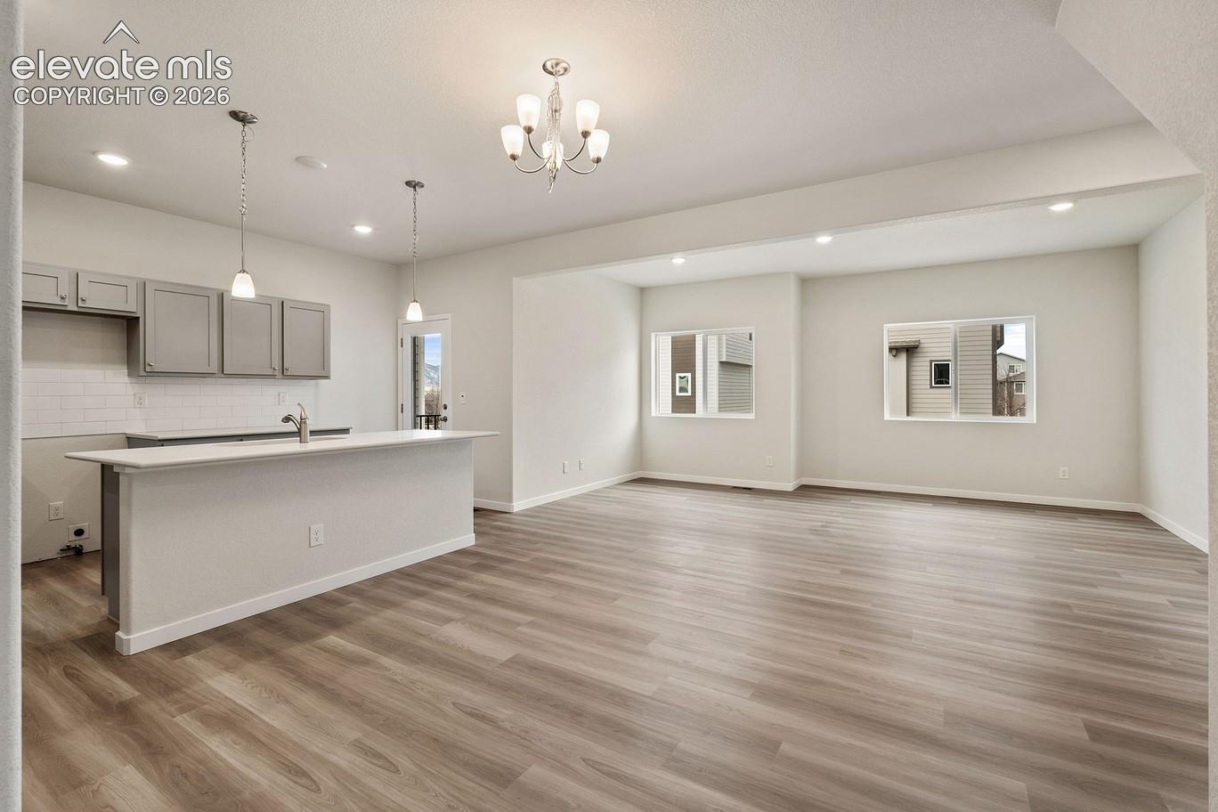 kitchen and living room with island, pendant lights, chandelier, and two windows in adjacent living area