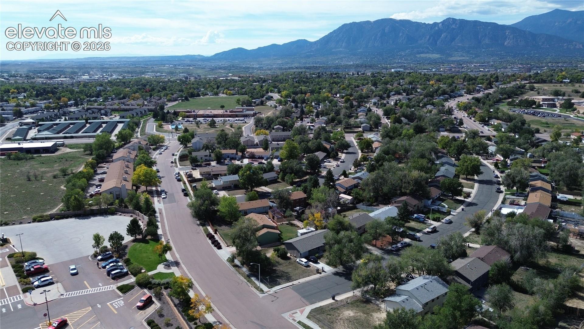 Neighborhood setting featuring residential streets, mature trees, and distant mountains