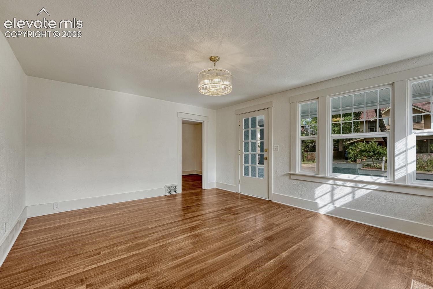 Hardwood flooring throughout, white trim, glass-paned door, and large multi-pane windows