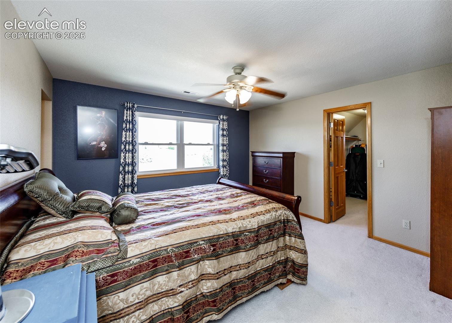 Recessed window with wood trim, ceiling fan light fixture, light-colored carpeting, and a built-in closet with wood-paneled door