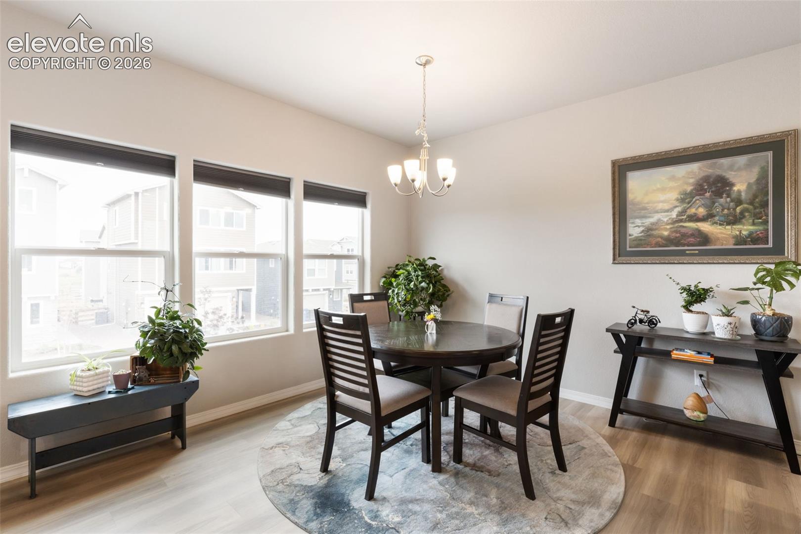 Dining space featuring a warm neutral color palette and abundant natural light from three large windows