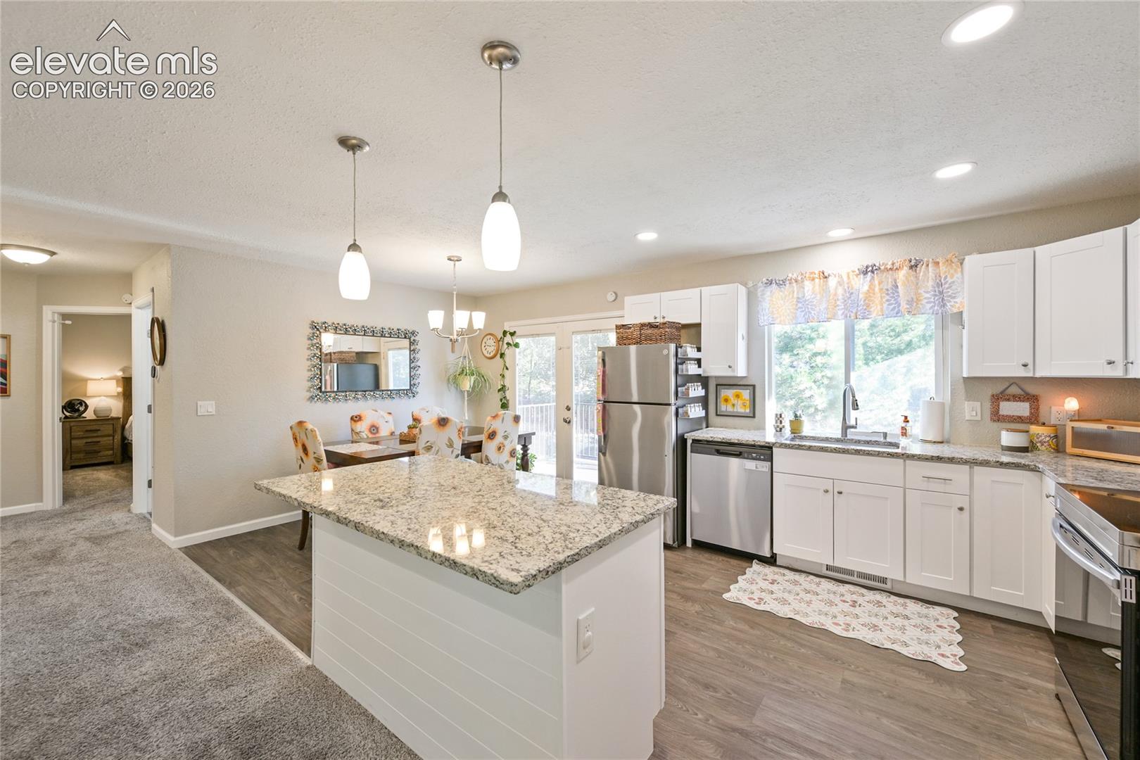 Kitchen featuring white shaker-style cabinetry, stone-surface countertops, a center island with shiplap detailing, stainless steel appliances, and wood-finish flooring