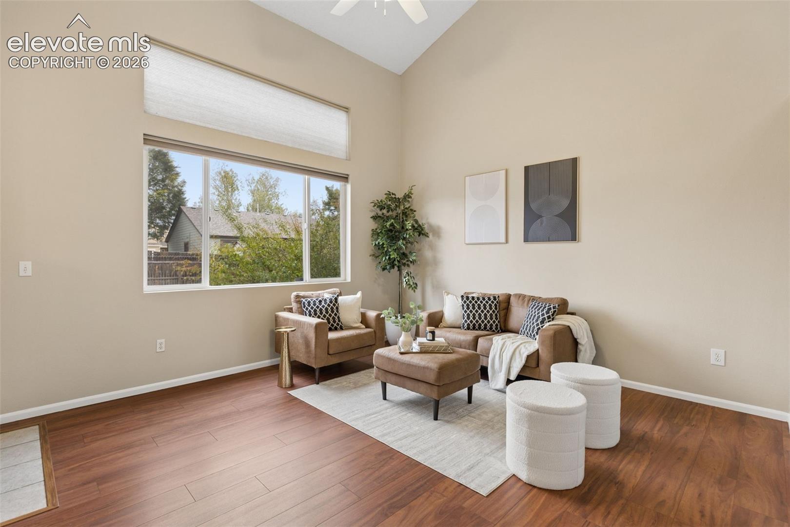 Vaulted ceilings featuring a high-reaching design, wood-finish flooring, and a large horizontal window with a secondary transom window above