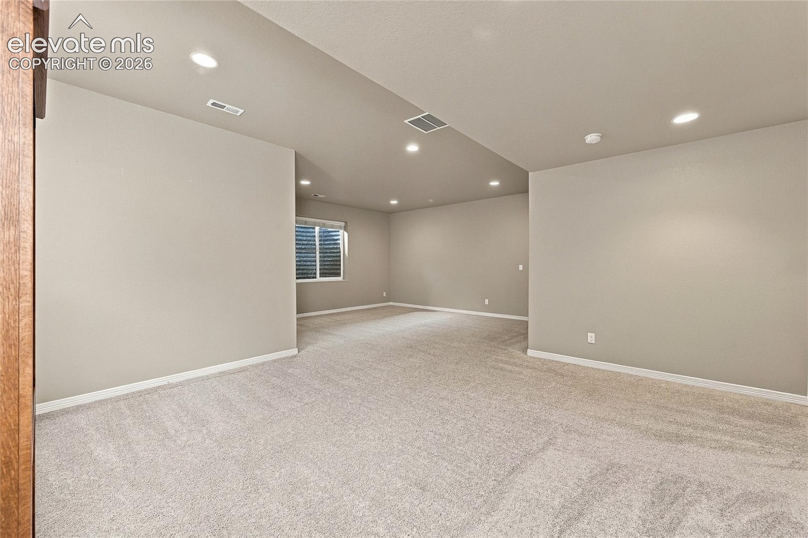 Neutral-toned interior space featuring carpeting, recessed lighting, and a single-pane window