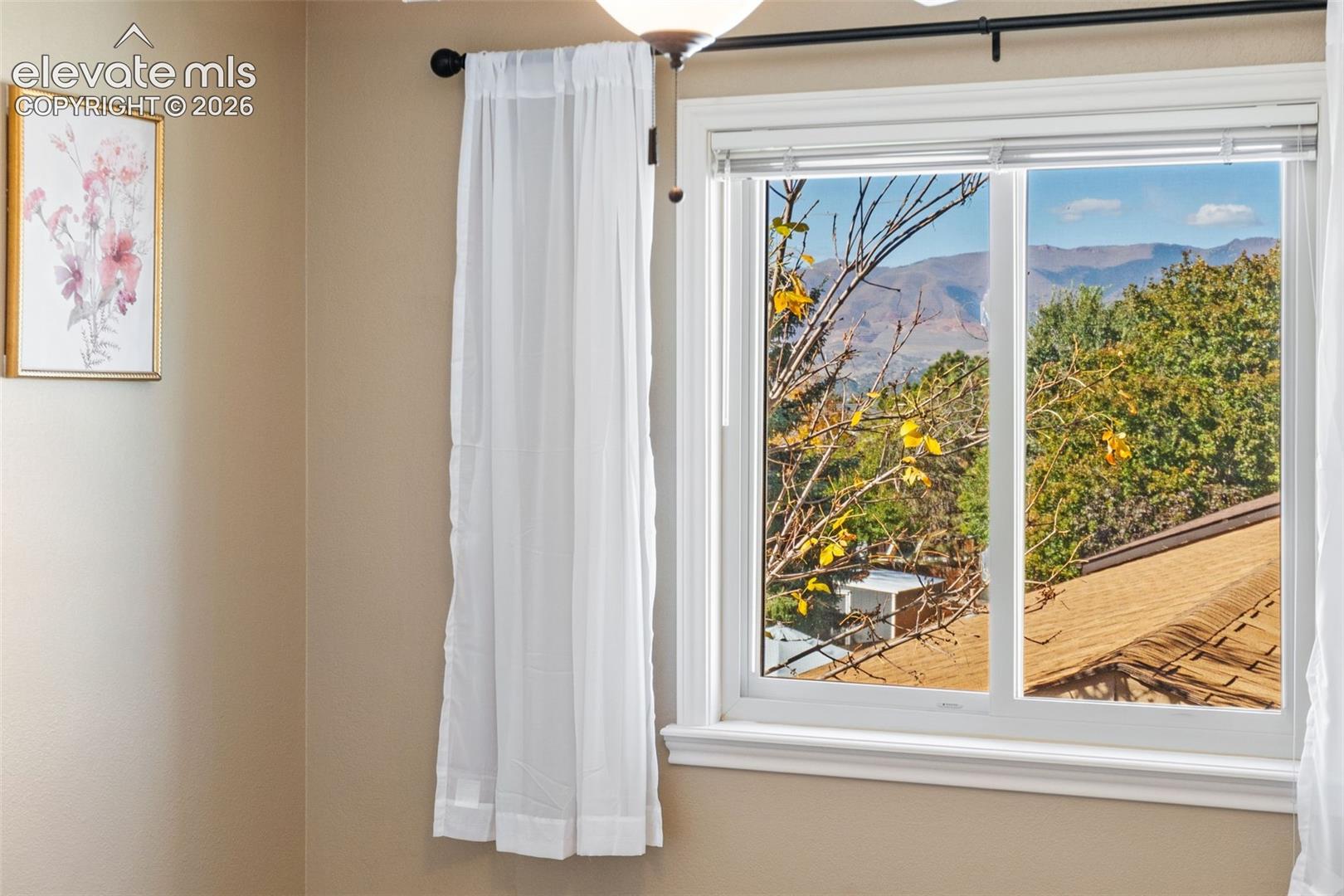 Sliding window with white trim frame and mountain landscape background