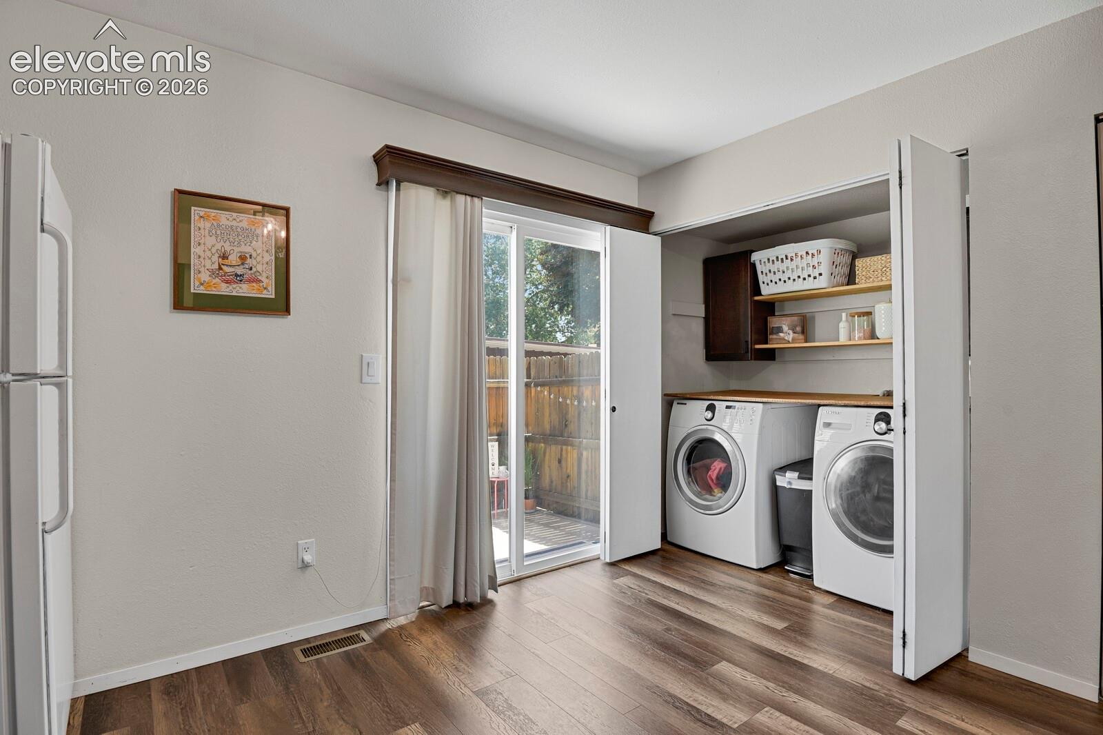 Wood-finish flooring with a dedicated laundry area featuring built-in shelving, a wood-finish countertop, and bi-fold doors