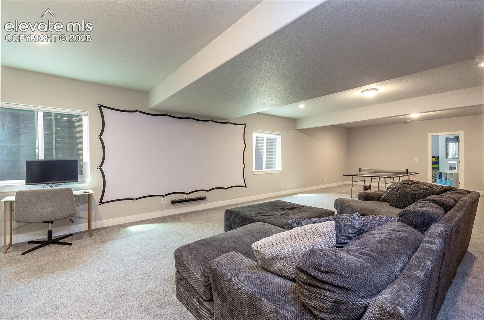 Basement Level Family Room featuring a projector screen, windows provide natural light, and light-toned carpeting
