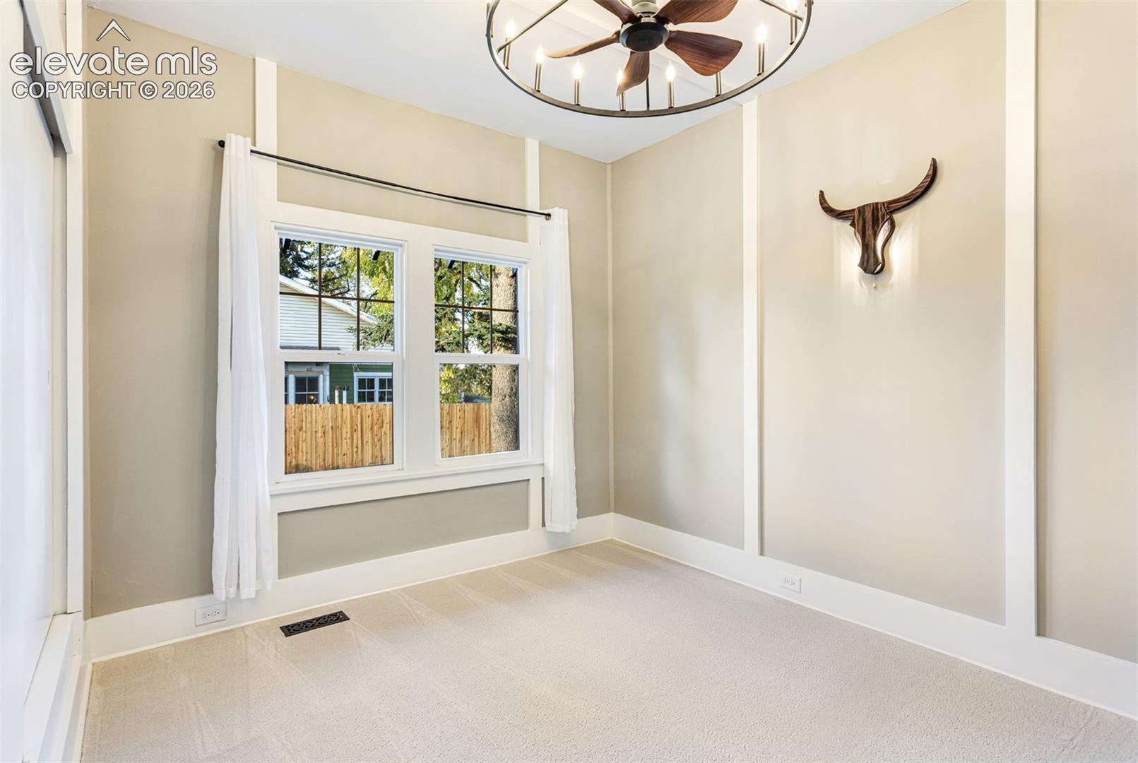 Room featuring a double window, baseboard trim, wall paneling, and neutral carpeting