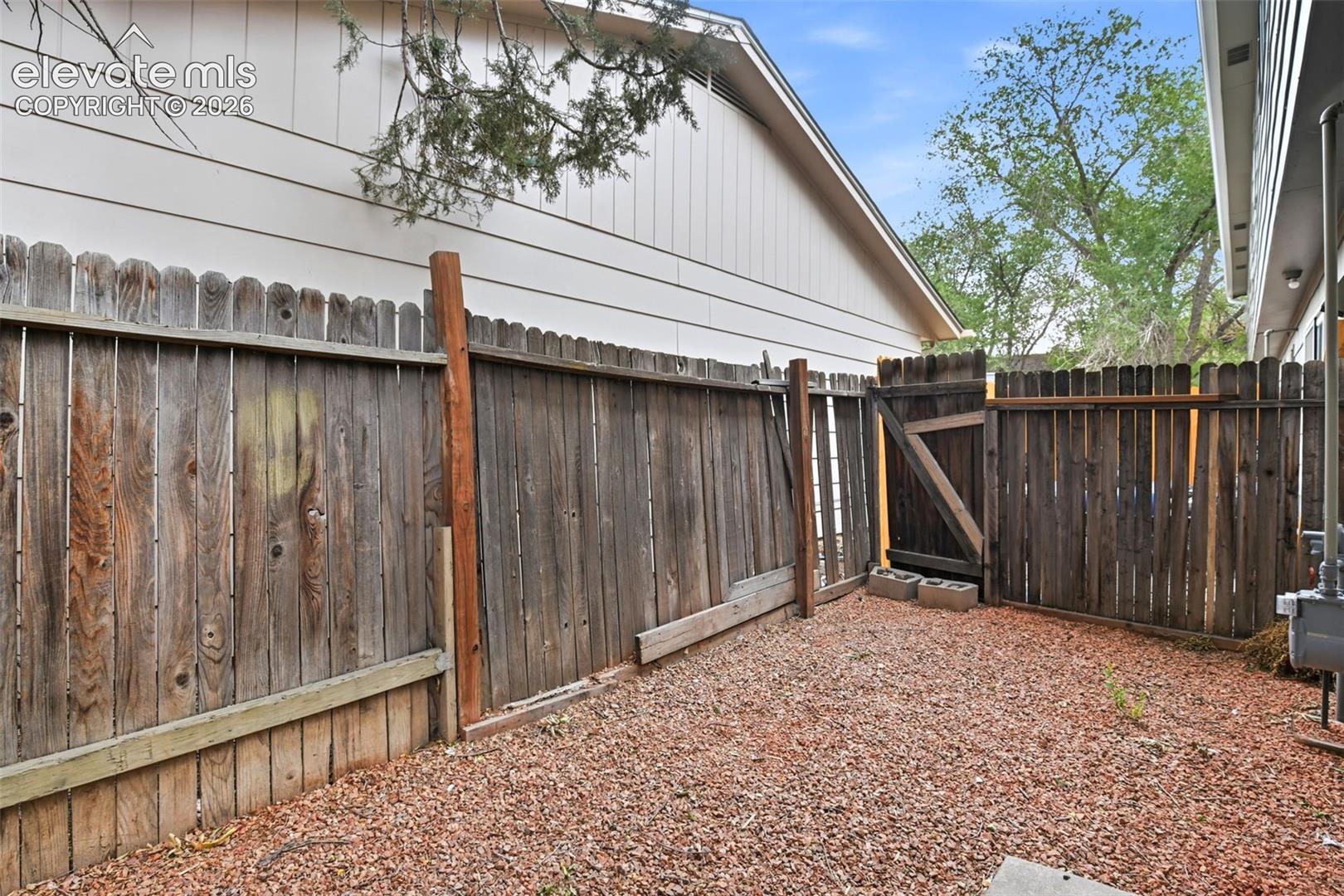 Fenced outdoor space featuring a wood privacy fence with gate and gravel ground cover