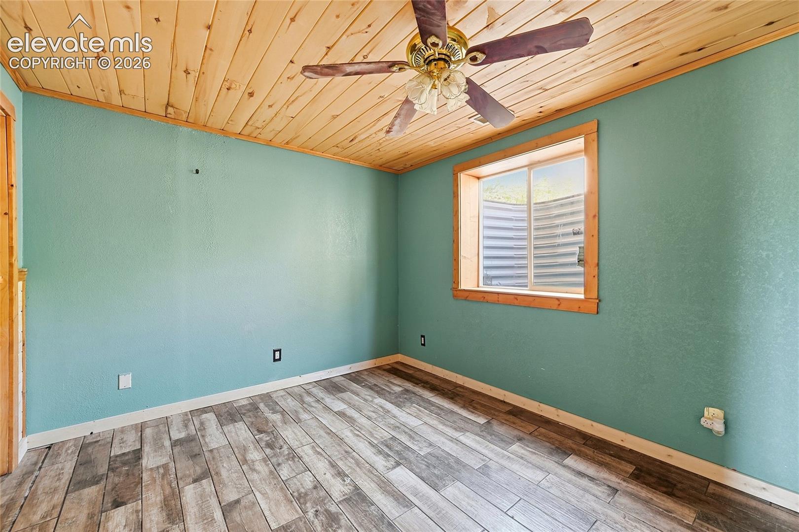 Wood-finish flooring, wood plank ceiling, window with wood trim, and a ceiling fan