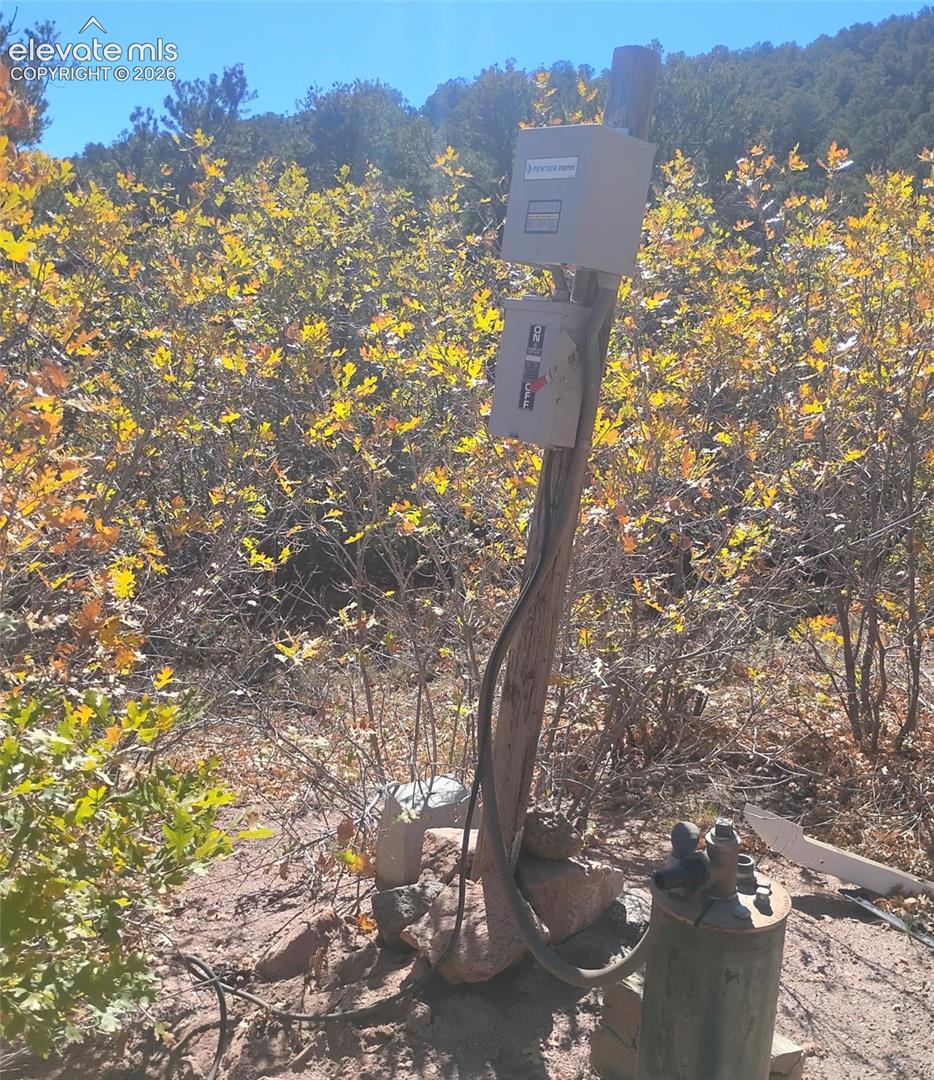 Utility connection point featuring an elevated electrical service panel and onsite well head casing