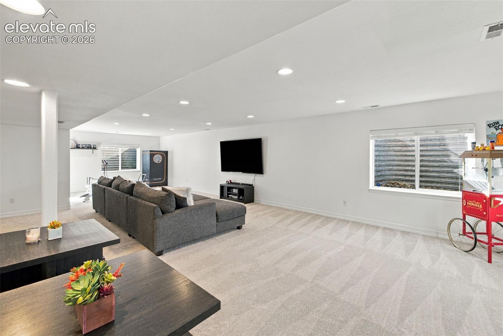 Open-concept interior featuring neutral wall-to-wall carpeting, recessed ceiling lighting, and multiple egress windows