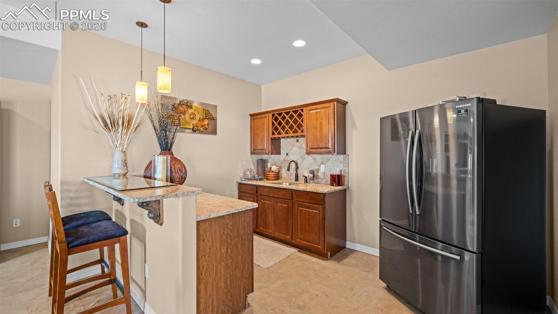 Wet bar with freestanding refrigerator, bar top, a peninsula, wood finish cabinetry, 