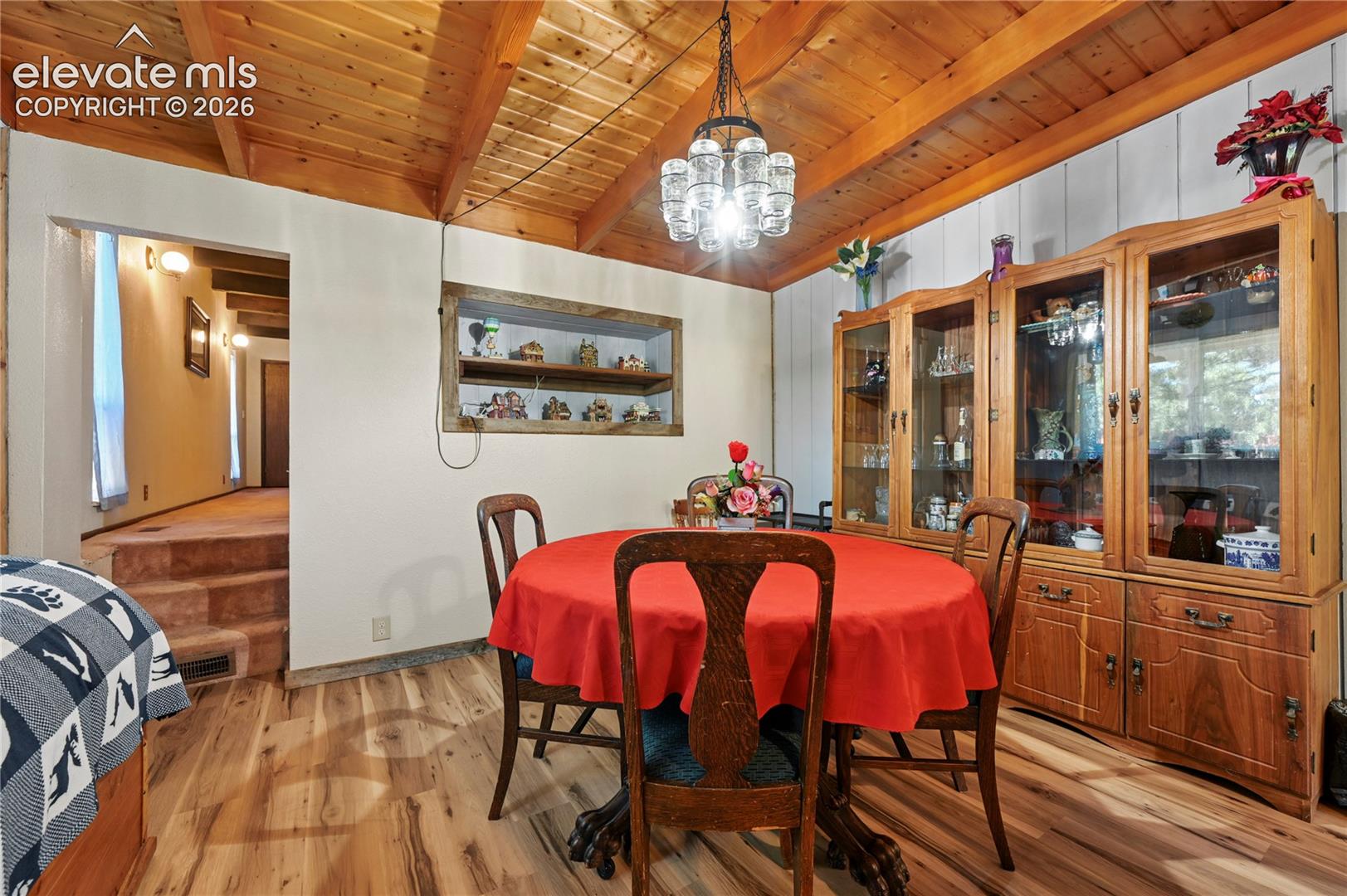 Vaulted wood-finish ceiling with exposed beams, wood-finish flooring, built-in wall niche, and paneling accents