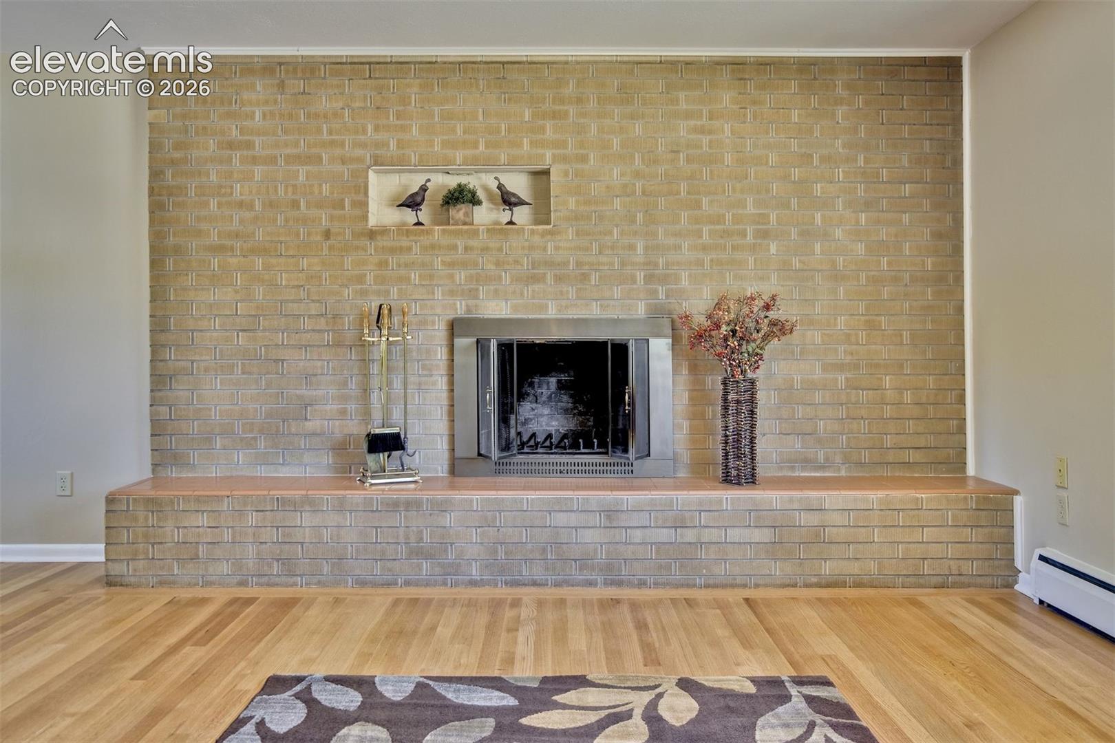 Full-height masonry brick fireplace featuring a tiered hearth, metal firebox surround, and a recessed display niche